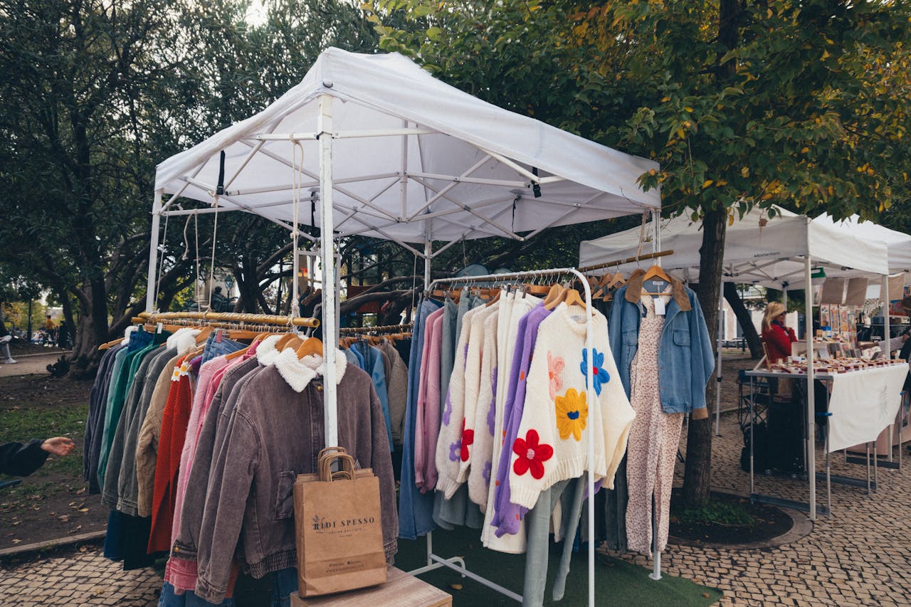Vibrant outdoor market showcasing colorful clothes on hangers under a canopy.