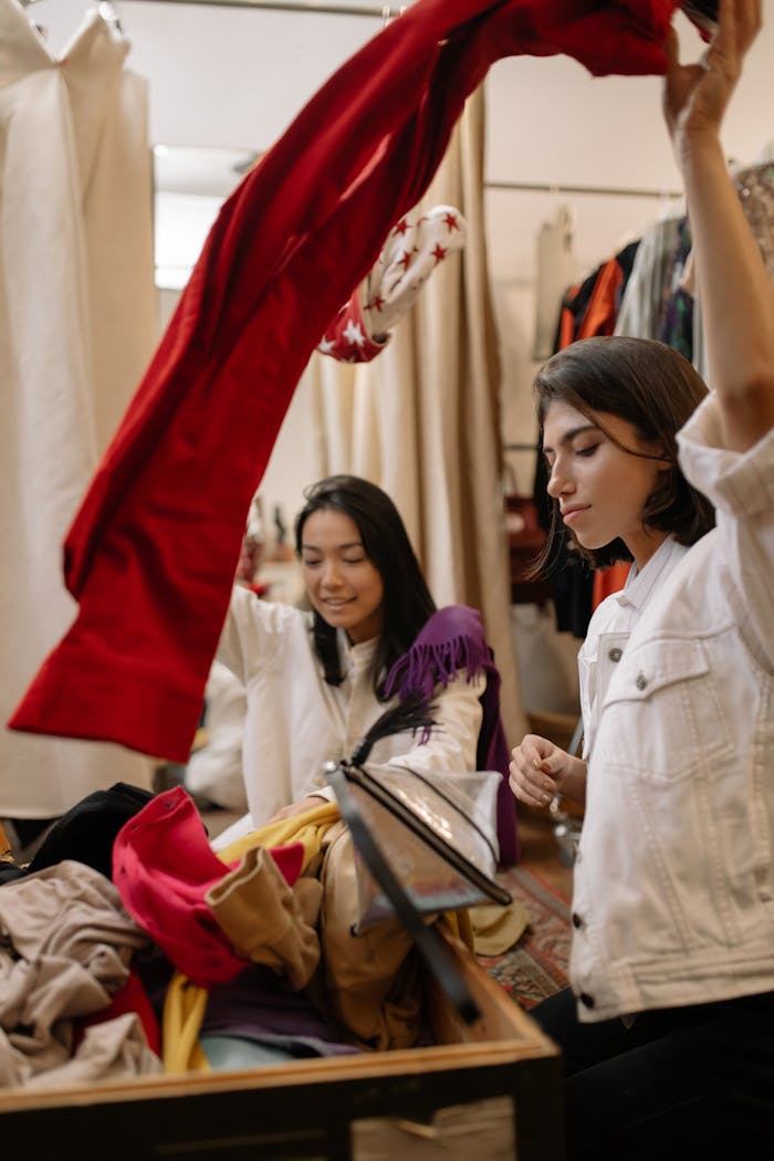 Two women enjoying a fun shopping day at a thrift clothing store.